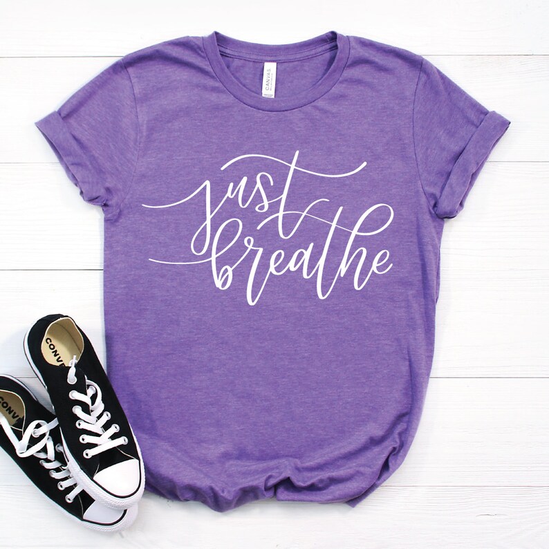 May include: Purple t-shirt with the text "just breathe" in white cursive lettering.