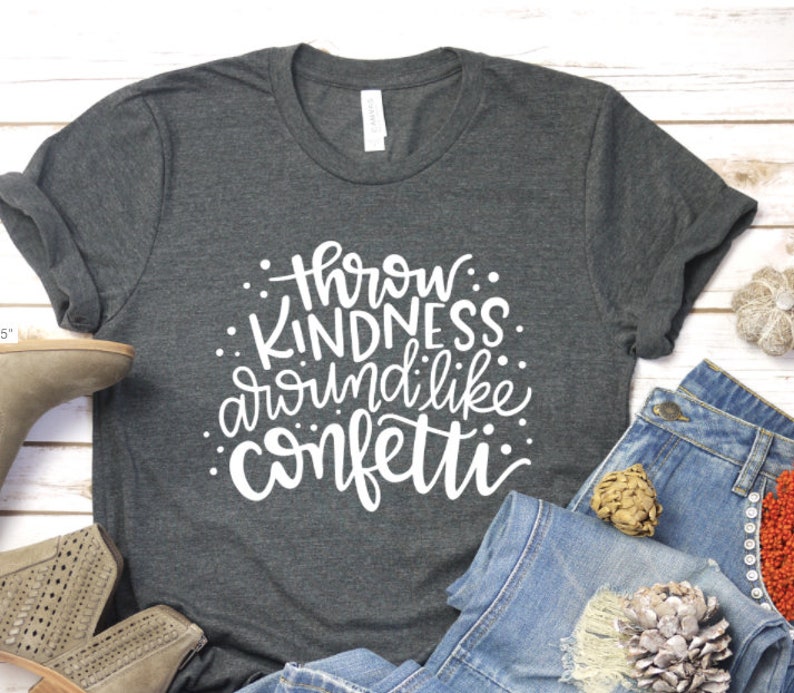 May include: A dark gray t-shirt with white text that reads "Throw Kindness Around Like Confetti".