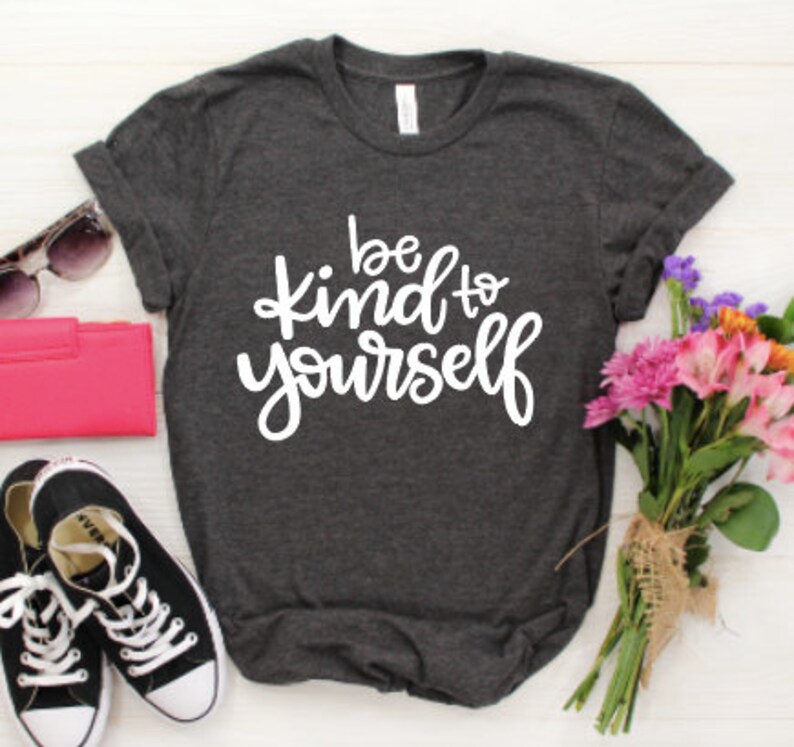 May include: A dark gray t-shirt with the text "be kind to yourself" in white lettering.