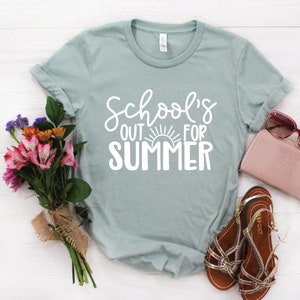 K&ouml;nnte beinhalten: Ein hellblaues T-Shirt mit dem Text "School's Out For Summer" in Wei&szlig;. Der Text enth&auml;lt eine Sonnengrafik.