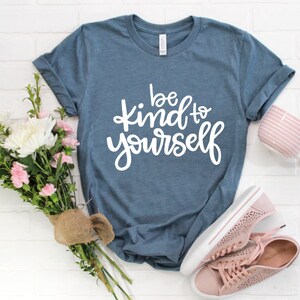 May include: A blue t-shirt with the text "be kind to yourself" in white lettering.