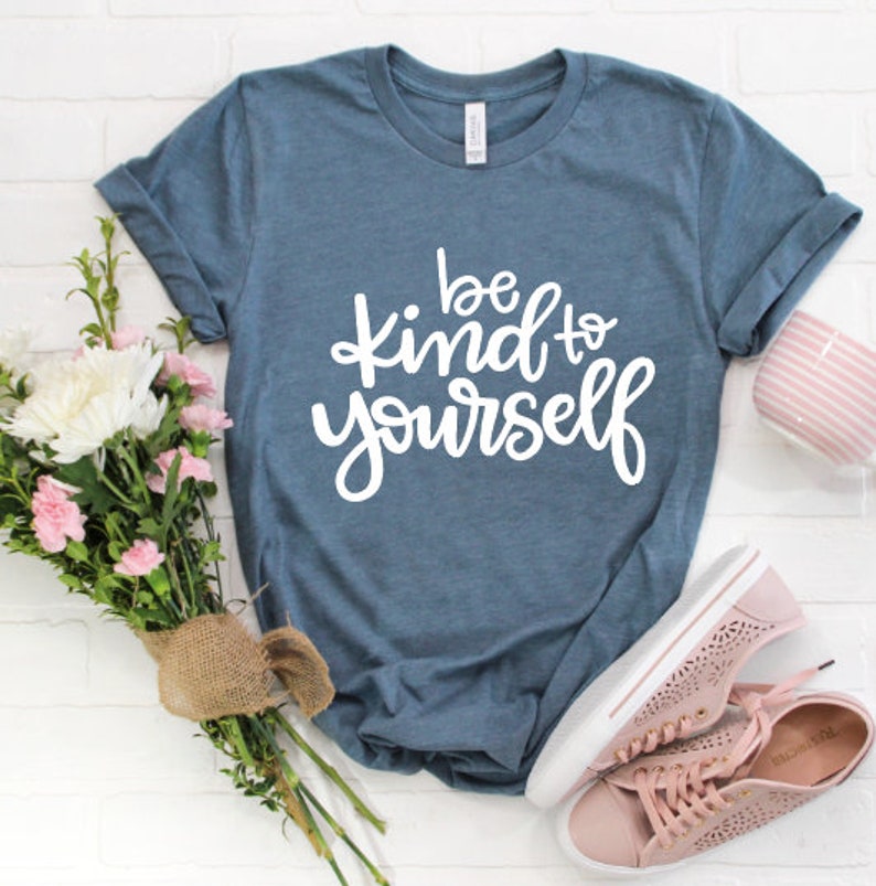 May include: A blue t-shirt with the text "be kind to yourself" in white lettering.