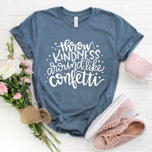 May include: A blue t-shirt with the text "Throw Kindness Around Like Confetti" in white lettering.