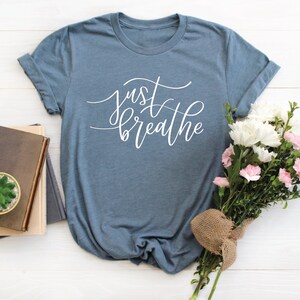 May include: A blue t-shirt with the text "just breathe" in white cursive lettering.