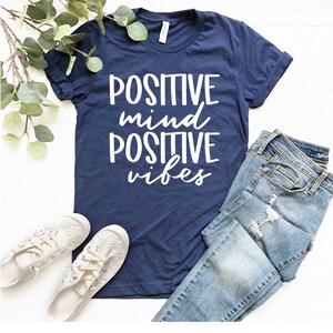 May include: A navy blue t-shirt with white text that reads "POSITIVE mind POSITIVE vibes".