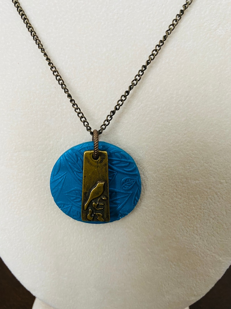 Stamped clay pendant with brass bird etched charm