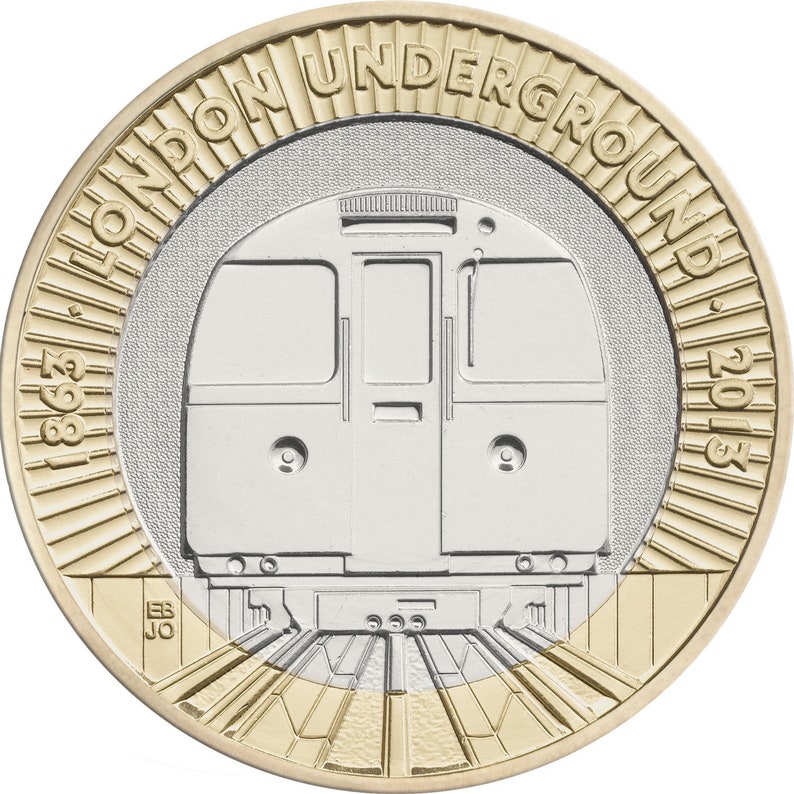 May include: A two-tone coin featuring a London Underground train. The coin has a gold outer ring with the text "LONDON UNDERGROUND" and the years "1963" and "2013". The center of the coin is silver with a detailed train design.