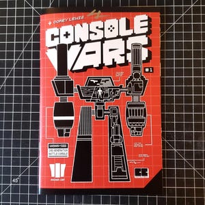 May include: A red comic book cover with a black and white illustration of a robot. The title of the comic is "Console Wars" and the issue number is #1. The text "Washari-5000 2nd Generation Battle Console" is printed on the cover.
