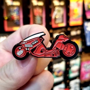 Puede incluir: Pin de esmalte rojo y negro de una motocicleta con las palabras "Coastal" y "Vania" en el lateral.