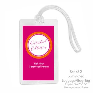 May include: Set of two laminated luggage or bag tags with a pink background and an orange circle with the text "Sisterhood Collection". The tags are 2 by 3.5 inches and can be personalized with a monogram or name.