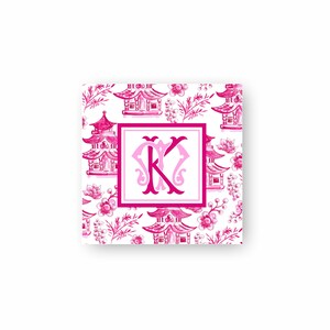 May include: A square card with a pink and white pattern featuring pagodas and a pink monogram "K" in the centre.