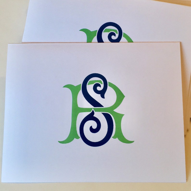May include: A white card with a green and blue monogram of the letters "S" and "R" intertwined.