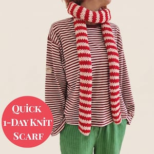 Könnte beinhalten: Ein rot-weiß gestreifter Strickschal ist um den Hals einer Person gelegt. Die Person trägt ein weinrot-weiß gestreiftes Langarmshirt und eine grüne Hose. Das Bild enthält den Text "Quick 1-Day Knit Scarf" in einem roten Kreis.