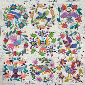 May include: A colorful quilt pattern featuring nine embroidered circles with birds and flowers. The quilt is titled "Of a Feather" by Sue Spargo.