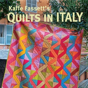 May include: A colorful quilt featuring a geometric zigzag pattern in shades of pink, orange, yellow, blue, and green. The book cover displays the text Kaffe Fassett's QUILTS IN ITALY and 20 designs from Rowan for patchwork and quilting.