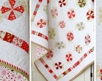 May include: A white quilt with a candy wrapper pattern in red, green, and beige. The quilt features a repeating design of candy-shaped motifs and is bordered with patterned fabric. The text "Candy Wrappers" is displayed at the bottom.