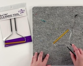 Könnte beinhalten: Eine graue quadratische Wollmatte und ein Reinigungswerkzeug mit gelber Silikonrolle, Metallrahmen und schwarzen Griffen. Die Verpackung des Werkzeugs ist mit Wool Mat CLEANING TOOL von The Gypsy Quilter beschriftet und zeigt das Werkzeug.