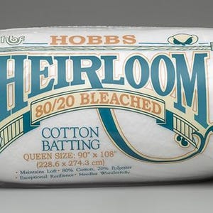 May include: A white package of Hobbs Heirloom 80/20 Bleached Cotton Batting for quilting. The package is labeled with the queen size, 90 inches by 108 inches, or 228.6 centimeters by 274.3 centimeters.