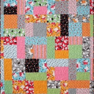 May include: A patchwork quilt with a variety of colorful fabrics, including floral prints, polka dots, stripes, and geometric patterns. The quilt is made up of squares and rectangles of different sizes, creating a visually interesting and textured design.
