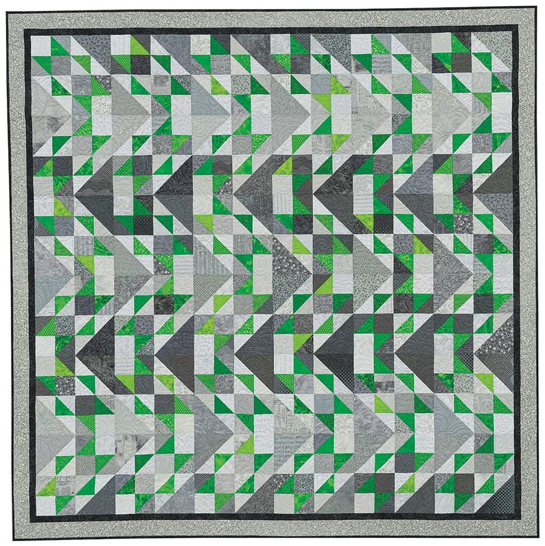 May include: A quilt with a geometric pattern of green and grey triangles. The quilt is made up of many smaller squares, each with a different pattern.
