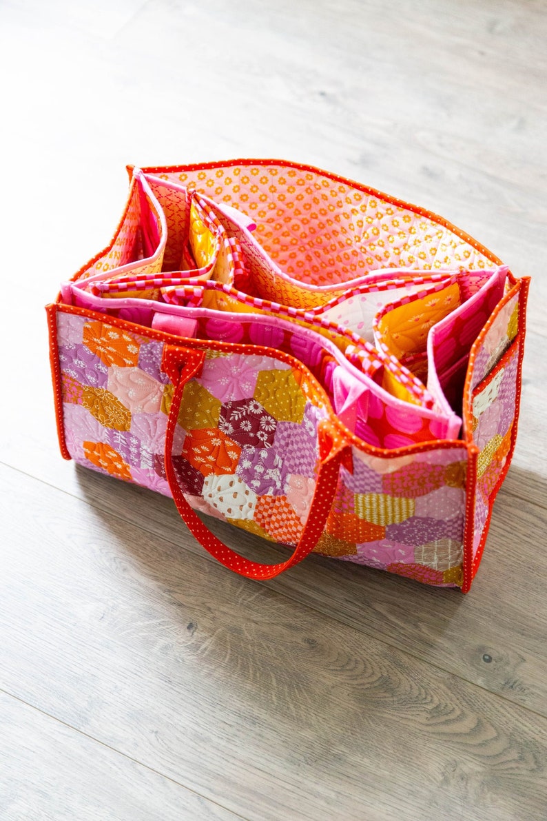 May include: A pink and orange patchwork tote bag with multiple pockets and a red handle.