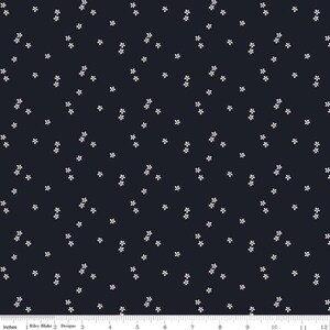 May include: Dark navy fabric with a repeating pattern of small, white, five-petal flowers. The flowers are scattered across the surface, creating a delicate and airy design. The fabric is measured in inches.