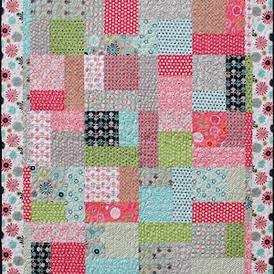 May include: A patchwork quilt with a variety of colorful fabrics, including pink, green, blue, and black. The quilt is made up of squares and rectangles of different sizes and patterns. The quilt is edged with a black and white floral border.