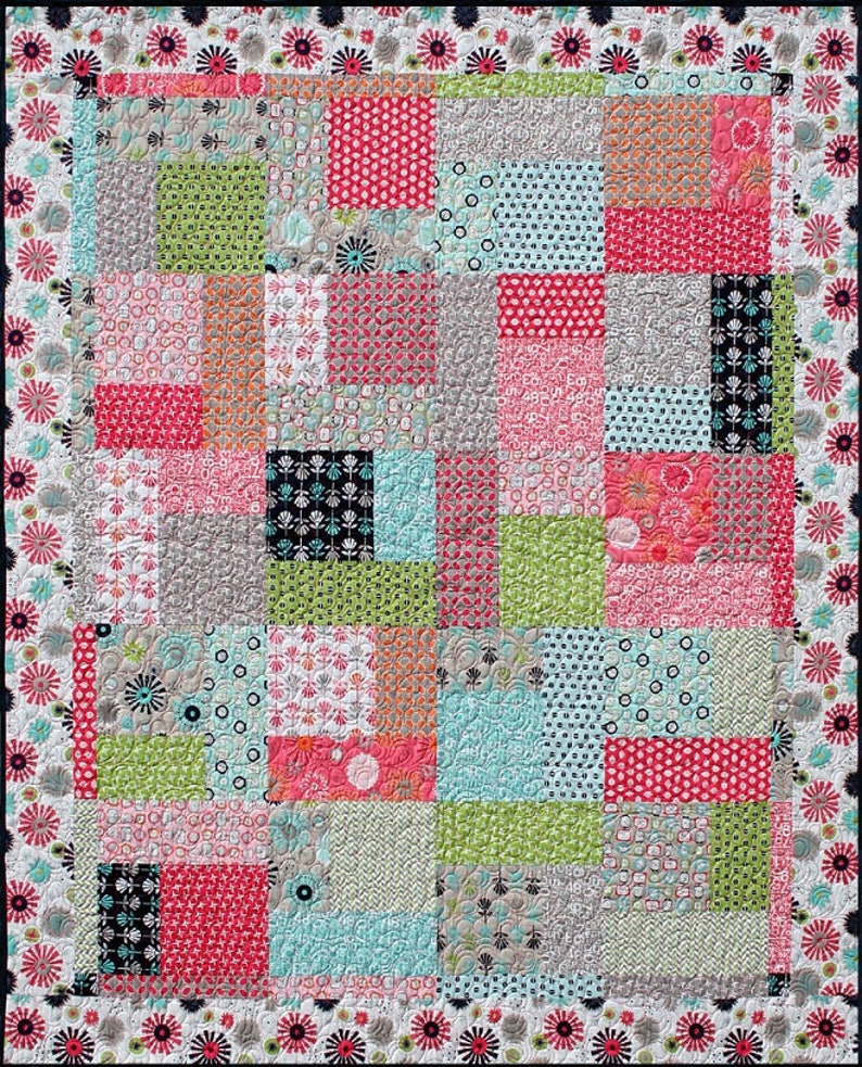 May include: A patchwork quilt with a variety of colorful fabrics, including pink, green, blue, and black. The quilt is made up of squares and rectangles of different sizes and patterns. The quilt is edged with a black and white floral border.