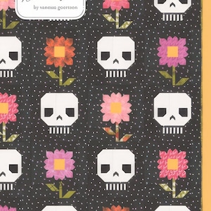May include: A quilting pattern featuring a black background with white skulls and colorful flowers. The pattern is titled "Pushing Up Daisies" and is from Lella Boutique by Vanessa Goertzen. #231