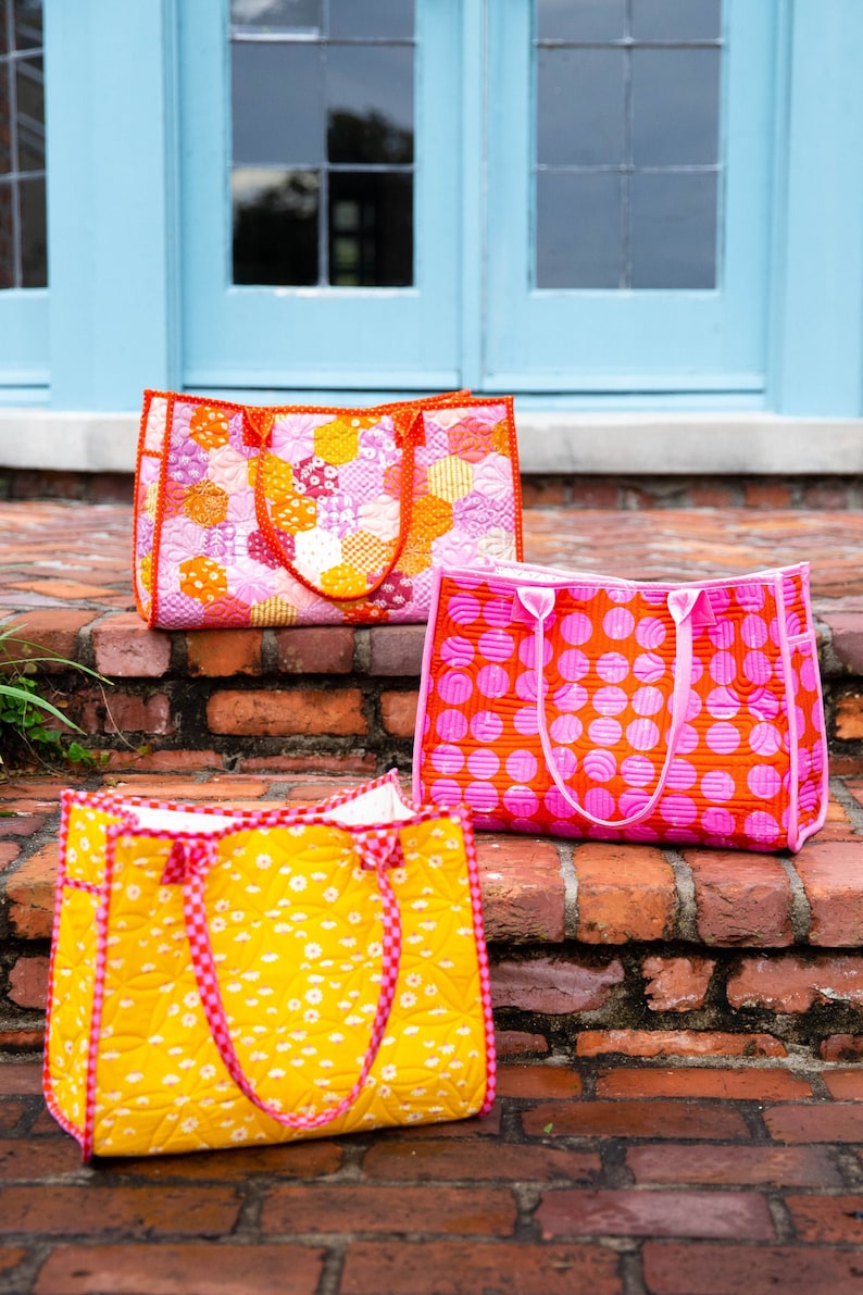 May include: Three quilted tote bags in different patterns. The top bag is pink and white with a geometric pattern. The middle bag is pink with large white polka dots. The bottom bag is yellow with a small white floral pattern.