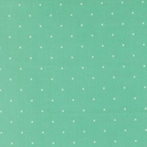 May include: A mint green fabric featuring a repeating pattern of small white crosses arranged in a grid. The textile has a visible woven texture, with each individual cross stitch mark evenly spaced across the solid colored surface.