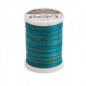 May include: A spool of Sulky 100% cotton mercerized thread featuring a variegated color pattern of teal, blue, and green. The white plastic spool has a label on top with the text Sulky, 100% Cotton, 733, 4087, and Made in Italy.