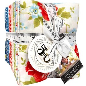 May include: A stack of fabric squares tied with a white measuring tape ribbon. The fabric features floral patterns in red, blue, and green on a white background. A round tag reads "50 Years" and a black tag reads "moda FABRICS + SUPPLIES".