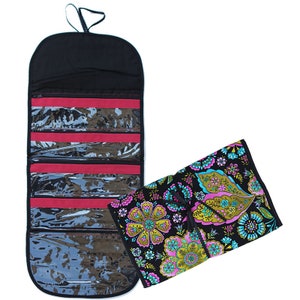 May include: A roll-up organizer case featuring a black exterior with a vibrant floral pattern in shades of pink, blue, and green. The interior is black with four clear plastic zippered compartments separated by red fabric strips and a hanging loop.