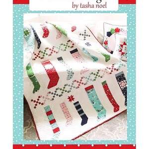 May include: A white quilt with a pattern of red, green, and blue stockings. The quilt is on a white surface with a red and white polka dot border. The text "Pixie Stockings by tasha noel #506" is in the bottom right corner.