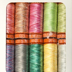 May include: A set of ten spools of thread in various colors, including orange, pink, green, blue, gray, and yellow. The spools are labeled "100% Cotton" and "Made in Italy".