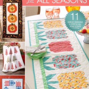 May include: A book cover featuring a collection of 11 quilted projects for all seasons. The cover shows three different quilt designs: a fall-themed pumpkin quilt, a winter-themed Christmas tree quilt, and a spring-themed tulip quilt. The text on the cover reads "Annie's Quilting Quilted Projects for All Seasons" and "11 Great Designs to Stitch All Year Long".