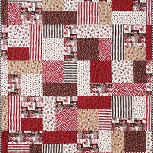 May include: A patchwork quilt with a variety of red, white, and brown fabrics. The quilt is made up of squares and rectangles of different sizes and patterns. The fabrics include stripes, polka dots, and floral prints.