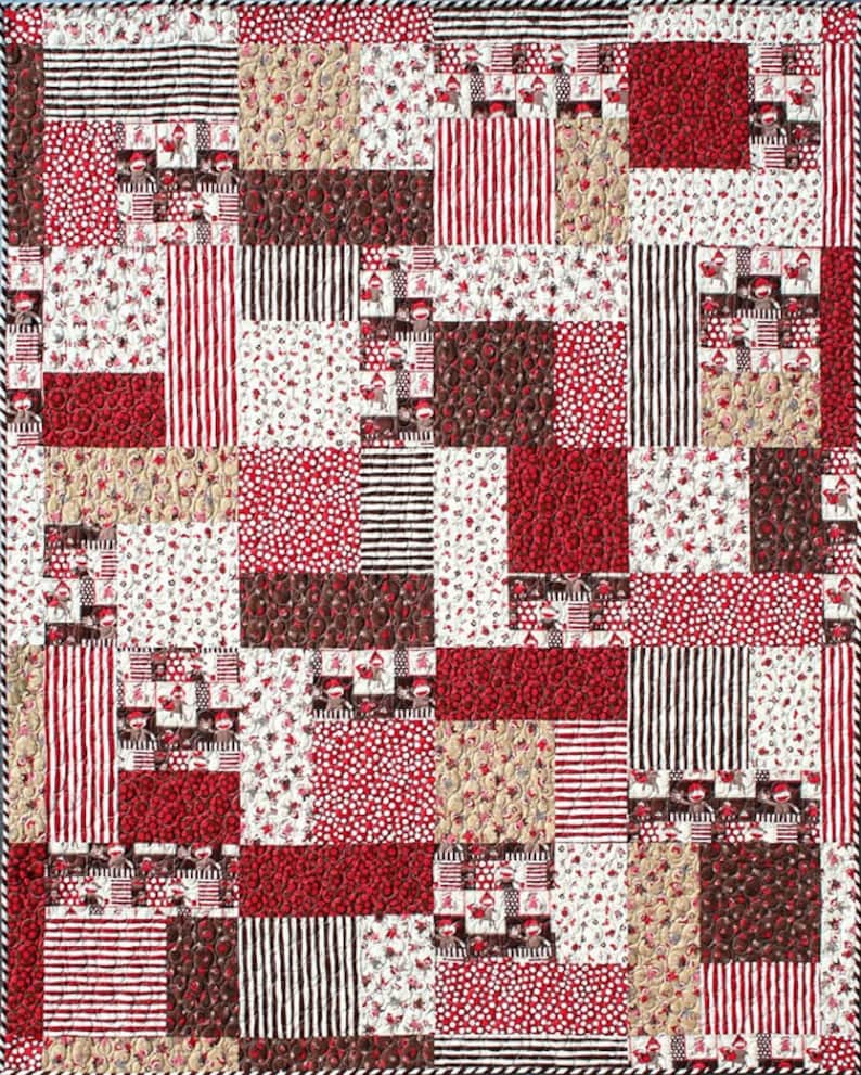 May include: A patchwork quilt with a variety of red, white, and brown fabrics. The quilt is made up of squares and rectangles of different sizes and patterns. The fabrics include stripes, polka dots, and floral prints.