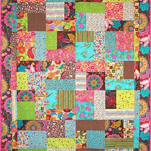 May include: A colorful patchwork quilt with a variety of floral and geometric patterns in shades of pink, green, blue, brown, and white. The quilt is made up of squares and rectangles of different sizes and is bordered with a pink and brown floral pattern.