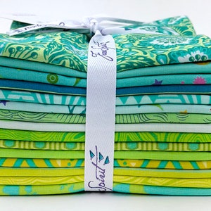 Op de afbeelding: Een stapel van 12 stofvierkanten in verschillende tinten groen en blauw met verschillende patronen. De stofvierkanten zijn met een wit lint aan elkaar gebonden. Het lint heeft de tekst "Sprout & Flourish" erop gedrukt.