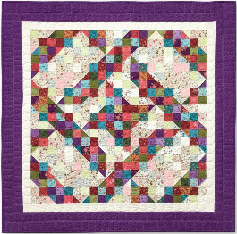 Pu&ograve; includere: Una trapunta viola e bianca con un design a patchwork che presenta vari motivi floreali in tonalit&agrave; di rosa, rosso, verde e blu.