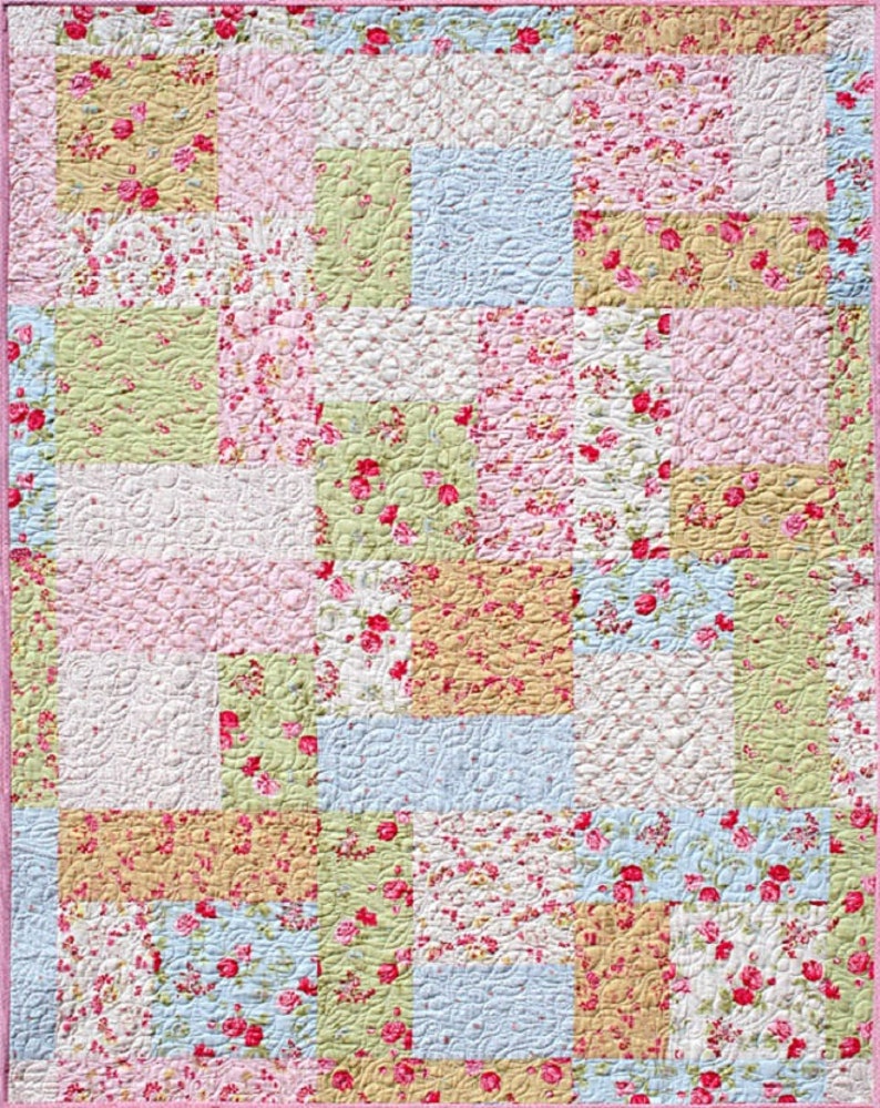 May include: A patchwork quilt with a floral pattern in shades of pink, green, blue, and yellow. The quilt is made up of squares of different sizes and is quilted with a swirl pattern.