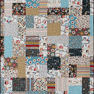 May include: A patchwork quilt with a variety of colorful fabrics featuring owls, flowers, and geometric patterns. The quilt is made up of squares and rectangles of different sizes and colors.