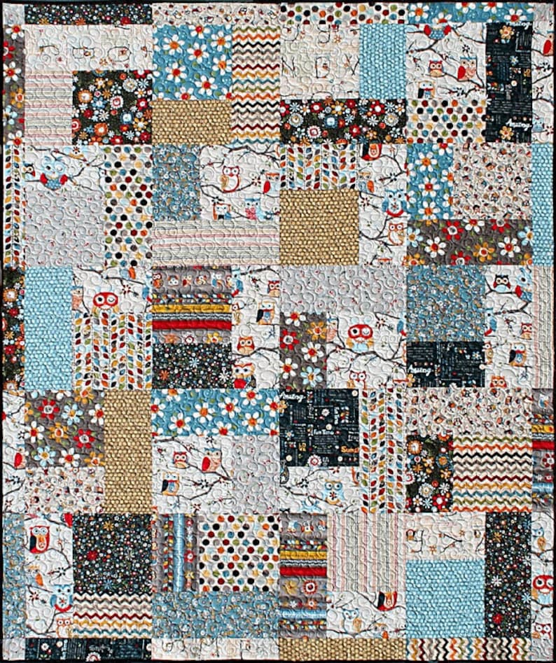 May include: A patchwork quilt with a variety of colorful fabrics featuring owls, flowers, and geometric patterns. The quilt is made up of squares and rectangles of different sizes and colors.