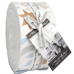 May include: Rolled fabric bundle featuring a repeating pattern of stars, leaves, and geometric shapes in shades of blue, tan, and gray on a white background. The bundle is tied with a ribbon printed with measurements and the "moda FABRICS + SUPPLIES" logo.