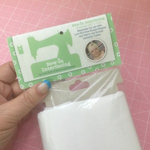 May include: A package of white sew-in interfacing by Lori Holt of Bee in my Bonnet. The packaging features a green sewing machine graphic and the text "Sew-in Interfacing". The package contains 3 yards (20 x 108 inches) of interfacing.