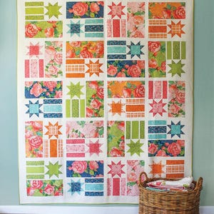 May include: A quilt pattern called "Constance" by Robin Pickens Quilt Patterns. The quilt is made up of a variety of colorful fabrics, including floral prints, stripes, and stars. The quilt is available in three sizes: lap, twin, and queen.