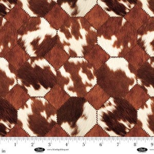 May include: A close-up of a fabric with a cowhide pattern. The design features brown and white patches arranged in a geometric pattern. The patches are stitched together with a dark thread, creating a textured surface. The fabric is measured in inches.