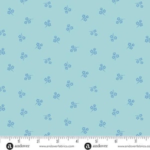 May include: A light blue fabric with a repeating pattern of small, light blue floral sprigs. The fabric has a ruler along the bottom edge, with the Andover Fabrics logo and website address printed on it.